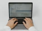 A person writing code on laptop with javascript libraries