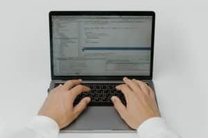 A person writing code on laptop with javascript libraries